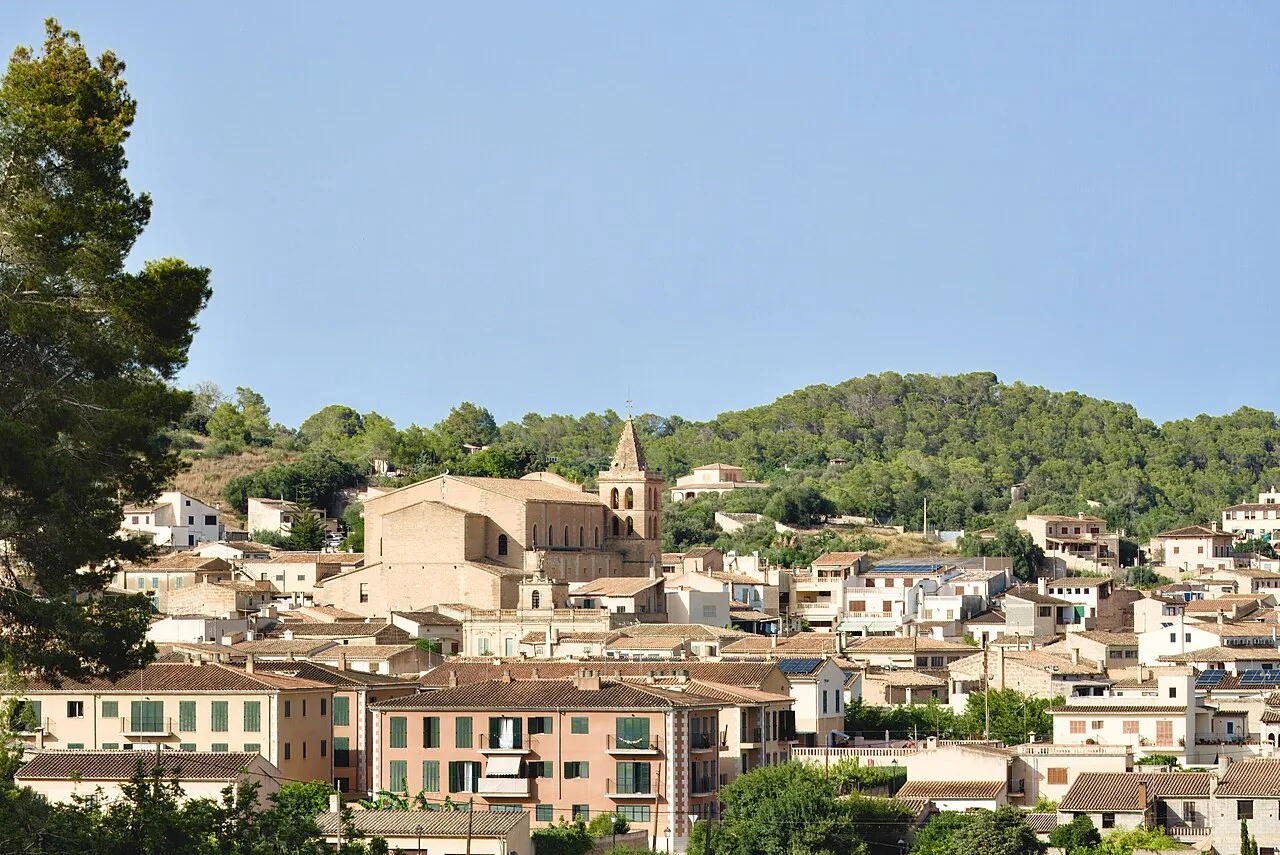Stadtansicht von Sant Joan mit Kirche und umliegenden Hügeln.