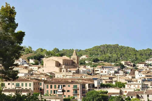 Stadtansicht von Sant Joan mit Kirche und umliegenden Hügeln.