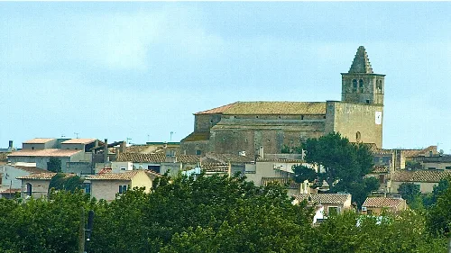 Stadtbild von Búger mit Kirche und Häusern, umgeben von Bäumen.